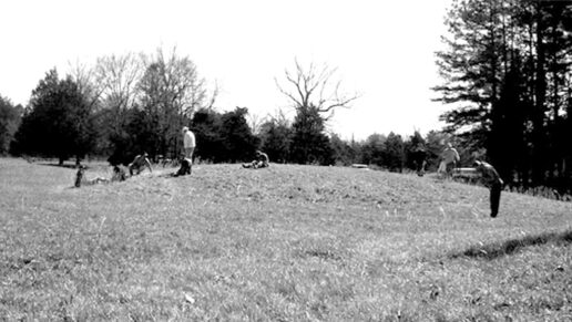 Black and white photo of people exploring pimple mounds